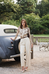 a lady in a floral printed silk shirt and a pair of white pants